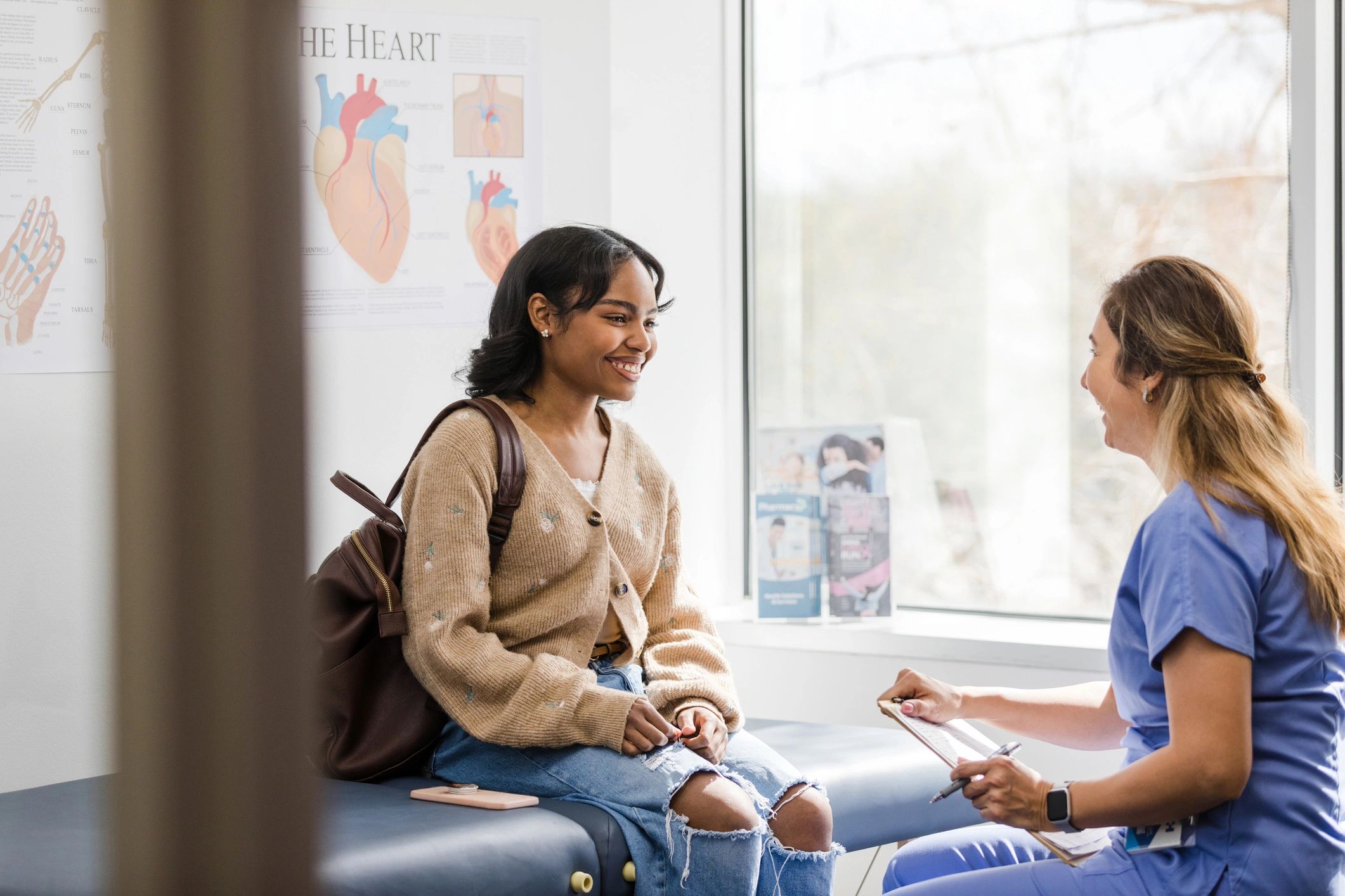 Young adult female patient smiles while listening to the nurse give an encouraging update regarding her medical exam